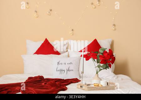 Plateau avec crêpes au fromage cottage et poinsettia de plante de Noël sur le lit dans la chambre Banque D'Images