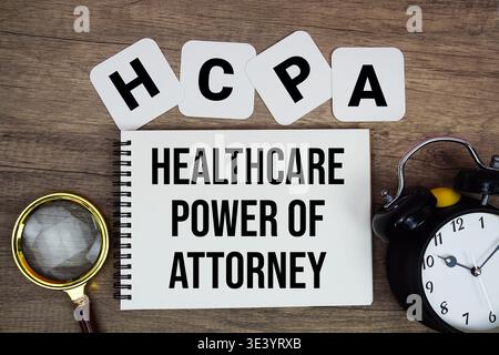HCPA Healthcare Power of Attorney texte écrit sur bloc-notes avec loupe et réveil sur fond en bois Banque D'Images