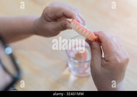 Vue en grand angle des mains d'un pensionné en prothèse adjointe. Stomatologie, concept de prothèse dentaire. Mise au point sélective. Concept de prothèse dentaire. Banque D'Images