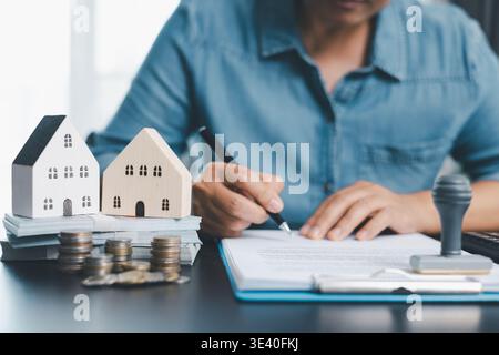 Courtier immobilier féminin présentant et conseillé de modéliser la maison, le détail du projet de construction dans le bureau, signer le contrat d'application de vente d'achat, accord Banque D'Images