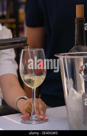 Au festival Erevan Wine Days, du vin blanc est versé dans un verre de dégustation de marque à partir d'une bouteille Banque D'Images