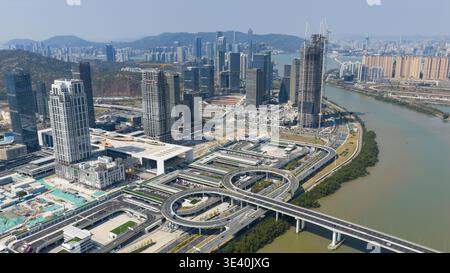 Vue aérienne de gratte-ciel modernes perçant la ligne d'horizon au-dessus d'un réseau complexe de routes et de ponts le long de la rivière scintillante, Zhoushan, Chine. Banque D'Images