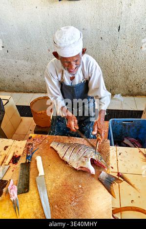 Un pêcheur coupe du poisson au marché aux poissons de Muscat Oman. C'est une scène animée avec des vendeurs locaux et des prises fraîches du jour. Banque D'Images