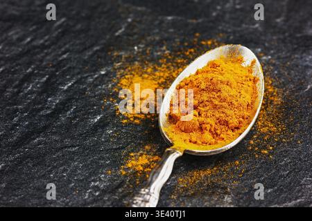 Rez-de curcuma curcuma ou en argent vintage cuillère sur la surface de la pierre noire Banque D'Images