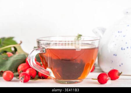 Thé parfumé aux baies d'aubépine d'automne. Boisson chaude biologique à base de plantes à base de baies d'aubépine de forêt sauvage, sur fond de bois blanc Banque D'Images