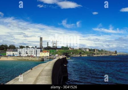Vue panoramique de St Andrews depuis la jetée montrant les bâtiments colorés du port, la passerelle côtière, les ruines de la cathédrale médiévale et les tours du château sous un brick Banque D'Images