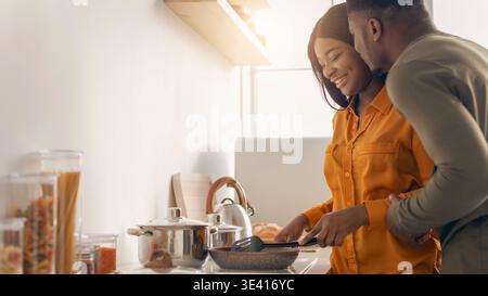 Portrait romantique du jeune couple afro-américain cuisant ensemble dans la cuisine Banque D'Images