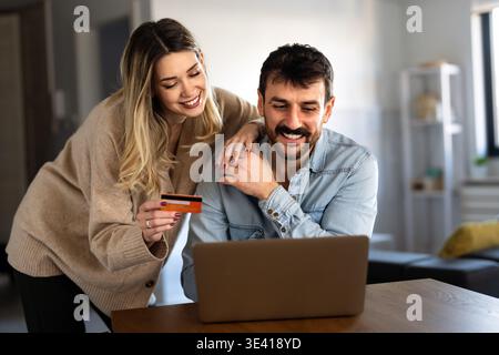 Heureux jeune diversifié, couple multiethnique budget de planification, lecture de bonnes nouvelles sur ordinateur portable à la maison Banque D'Images