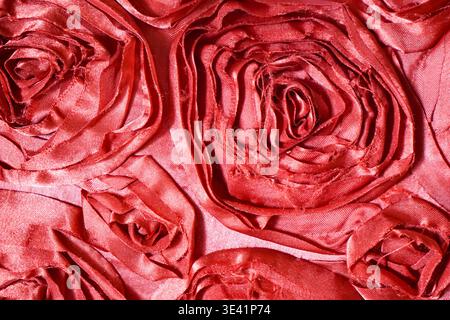 Gros plan de tissu satiné plié en motifs floraux ressemblant à une rose avec un éclat riche et une texture superposée. Banque D'Images