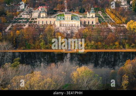 Vue aérienne de l'opulent Palais sur l'eau reflétant dans le lac tranquille au milieu des teintes dorées de l'automne, Varsovie, Voïvodie de Masovie, Pologne. Banque D'Images
