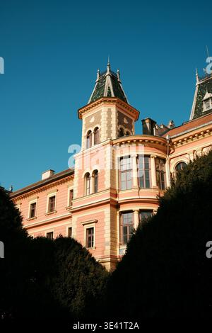 Bâtiment historique rose avec des tours décoratives et une façade ornée sous le ciel bleu à Sombor, Serbie. Concept européen d'architecture et de patrimoine culturel. Banque D'Images