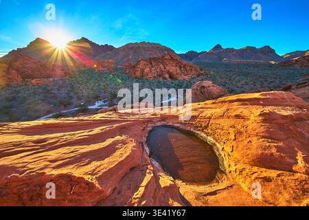 Redstone Dune Desert Tinaja au lever du soleil avec Sunburst et eau dans le Nevada Banque D'Images