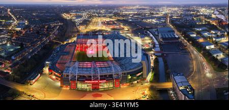 Large panorama aérien du stade de football Old Trafford illuminé la nuit, montrant la zone industrielle environnante de Trafford Park, Manchester, Royaume-Uni. Banque D'Images