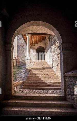 Vue évocatrice de la 'Scalette Vecchie' à Feltre, entrant de Porta Pusterla. L'arche en pierre encadre l'escalier historique avec un plafond en bois A. Banque D'Images
