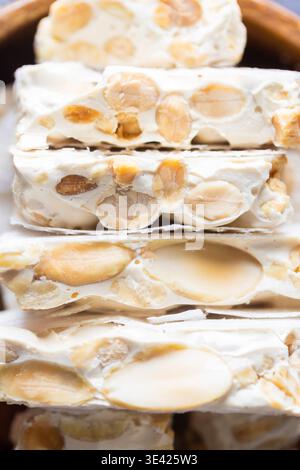 Un gros plan capture magnifiquement une pile de turron dur espagnol traditionnel, connu sous le nom de Turron de Alicante, mettant en valeur sa texture riche avec abundan Banque D'Images