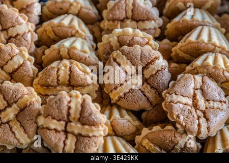 Un gros plan de Leipziger Lerchen (boules de sablés de massepain côtelées) dans une boulangerie : variétés claires et foncées empilées étroitement dans le présentoir. Leipzig, Saxe, Allemagne Banque D'Images