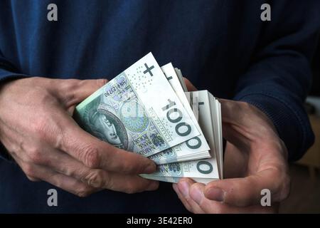 Acheter avec des économies. Un homme tient des billets de banque polonais de cent zloty dans ses mains. Banque D'Images