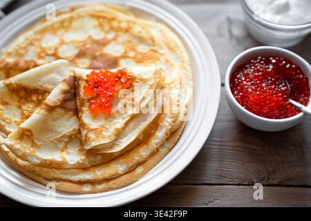 Crêpes minces faites maison avec du caviar rouge extrêmement rapproché, détaillé. Crêpes salées avec caviar de poisson de saumon. Déjeuner traditionnel de la semaine des crêpes Maslenitsa Banque D'Images