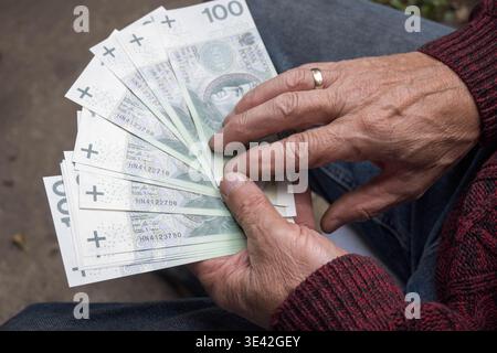 Un homme âgé tient entre ses mains de l'argent polonais, une pension. Banque D'Images