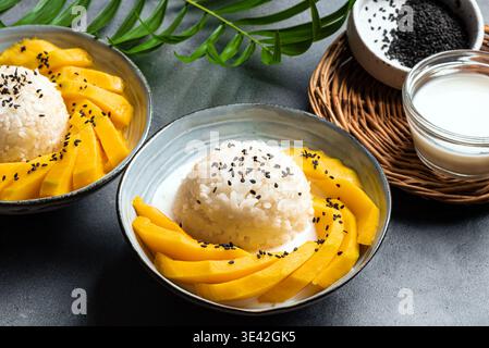 Riz collant à la mangue avec lait de coco et sésame noir dans des bols. Repas thaïlandais traditionnel. Khao niao mamuang. Banque D'Images