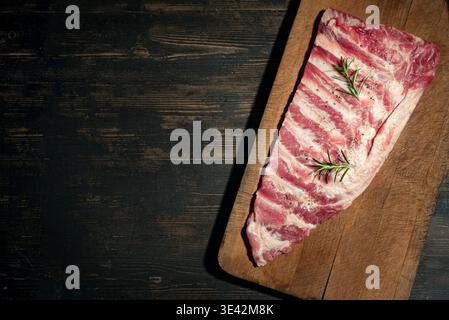 Côtes de porc crues prêtes à cuire, sur fond de bois, vue de dessus, espace copie. Sparerib de porc, modèle de recette. Banque D'Images
