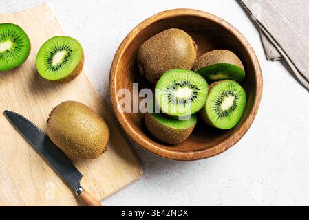 Kiwi fruits dans un bol en bois. Gros fruits entiers et demi-morceaux de kiwi vert. Kiwi mûr frais. Alimentation saine biologique. Banque D'Images