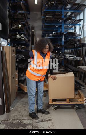 Femme logistique et ouvrier d'entrepôt souffrant de maux de dos après manipulation manuelle, levage et transport de boîte en carton lourde. Banque D'Images