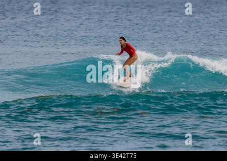Femme surfeuse en maillot de bain rouge chevauche sur la vague dans l'océan tropical Banque D'Images