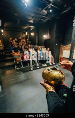 Interprète tenant Handpan dans Blackbox Theater, éclairage tamisé et sièges étagés avec attentif. Banque D'Images