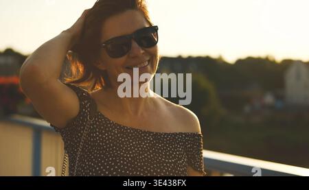 Attrayante jeune femme marche au coucher du soleil. Joyeux portrait féminin souriant au coucher du soleil Banque D'Images