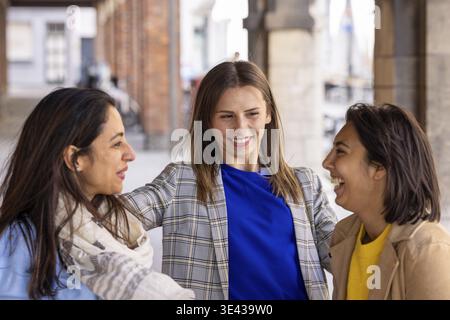 Trois jeunes femmes passent un bon moment à l’extérieur, où elles rient et bavardent dans un environnement urbain Banque D'Images