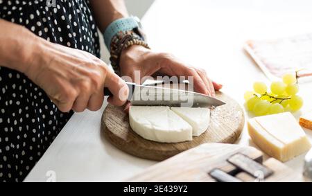 Fille coupant le fromage sur Une planche pour Une planche à fromage et plaçant le fromage Brie sur Une assiette Banque D'Images