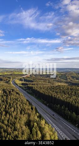 Cette photographie aérienne verticale capture l'autoroute E42 serpentant à travers les forêts denses de la région des Hautes Fagnes près d'Emmels, en Belgique. L'autoroute, Banque D'Images