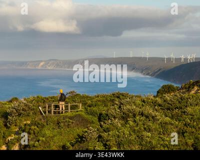 Sharp point, Albany, Australie occidentale – 8 novembre 2023 : une personne se tient devant un belvédère surplombant la côte avec des éoliennes au loin. Banque D'Images