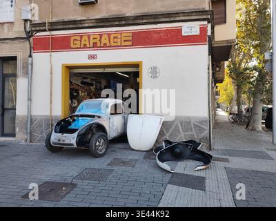 Une Volkswagen Beetle vintage subit une restauration dans un petit garage d'angle à Barcelone, avec son capot et ses ailes enlevés pour la carrosserie et la peinture. Banque D'Images