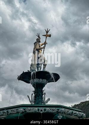 Une statue d'un chef inca dans une fontaine est mise en évidence contre un ciel nuageux sur la Plaza de Armas del Cusco. Banque D'Images