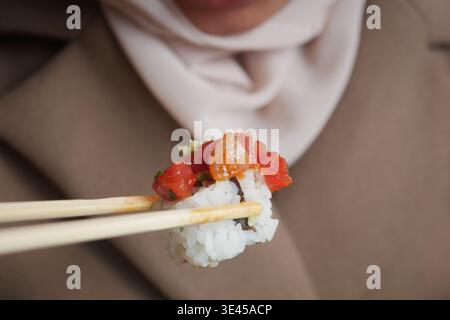Femme mange des sushis avec des baguettes dans un cadre décontracté Banque D'Images