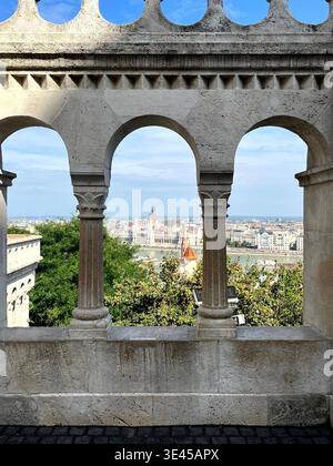Vue du Parlement hongrois à travers les arches de pierre du Bastion des pêcheurs Budapest Banque D'Images