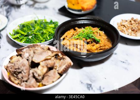 Pattes de poulet cuites à la vapeur avec gingembre et échalotes dans un pot d'argile, poitrine de porc braisée et sauté Banque D'Images