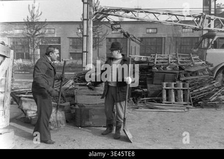 Sloviansk, avril 1989, cour d'usine AIZ. Les directeurs d'usine effectuent activement des tâches manuelles exigeantes lors d'un événement traditionnel de nettoyage de volontaires subbotnik au printemps. Les hommes dévoués utilisent de lourdes pelles et des outils essentiels pour nettoyer la cour industrielle des débris de construction et organiser des caisses en bois éparpillées. Cette photographie très authentique illustre magnifiquement l'engagement authentique de la direction de l'entreprise envers le travail d'équipe physique et le maintien des espaces extérieurs locaux dans le Donbass paisible. Banque D'Images