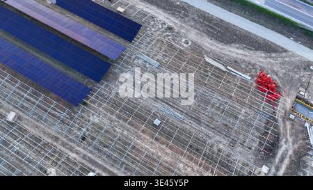 Centrale solaire à grande échelle en construction, avec des réseaux de modules photovoltaïques installés sur de vastes systèmes de rayonnage au sol, pr Banque D'Images