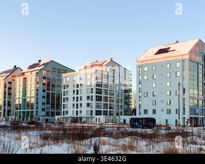Immeubles d'appartements modernes avec panneaux solaires sur un toit enneigé sous un ciel bleu clair lors d'une belle soirée d'hiver en Finlande Banque D'Images