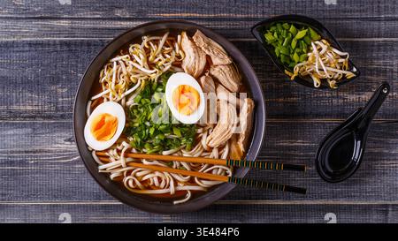 Soupe ramen japonais avec du poulet, l'oeuf, la ciboulette et sprout sur fond de bois sombre. Banque D'Images