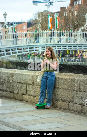 Jeune femme jouant au sifflet traditionnel en étain sur les quais Liffey pendant la Saint Patrick à Dublin en Irlande. Banque D'Images
