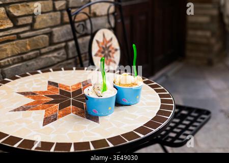 Gelato dans des gobelets en papier écologiques jetables placés sur une table de terrasse de café. Style de vie en plein air estival avec dessert froid sucré et daylig naturel Banque D'Images