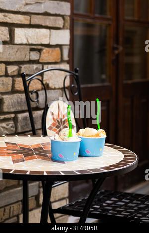 Deux gobelets en papier de crème glacée coupée sur une table en métal urbain contre un fond de mur de briques rouges classique. Cuisine de rue de ville et café industriel te Banque D'Images