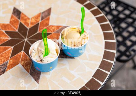 Vue de dessus plat de gobelets en papier remplis de cuillères à crème glacée colorées sur une table de café. Perspective aérienne d'un dessert d'été sucré rafraîchissant avec Banque D'Images