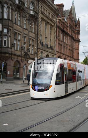 Un tramway blanc moderne CAF Urbos 3 sur le réseau de tramways d'Édimbourg passant devant l'architecture victorienne historique en grès dans une rue de la ville d'Édimbourg Banque D'Images