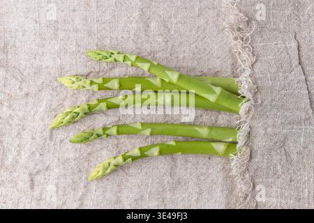 Asperges vertes fraîches sur fond de lin espace de copie. Collection de légumes de printemps. Nourriture saine. Banque D'Images