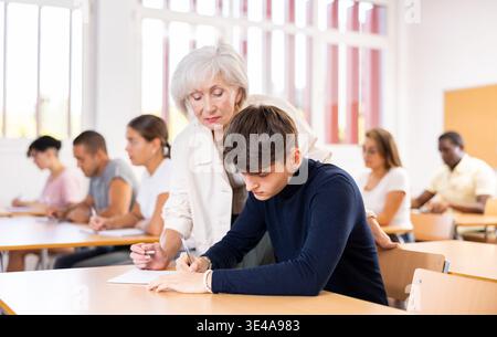 Enseignante senior femme aidant un étudiant jeune homme avec la solution de tâche Banque D'Images